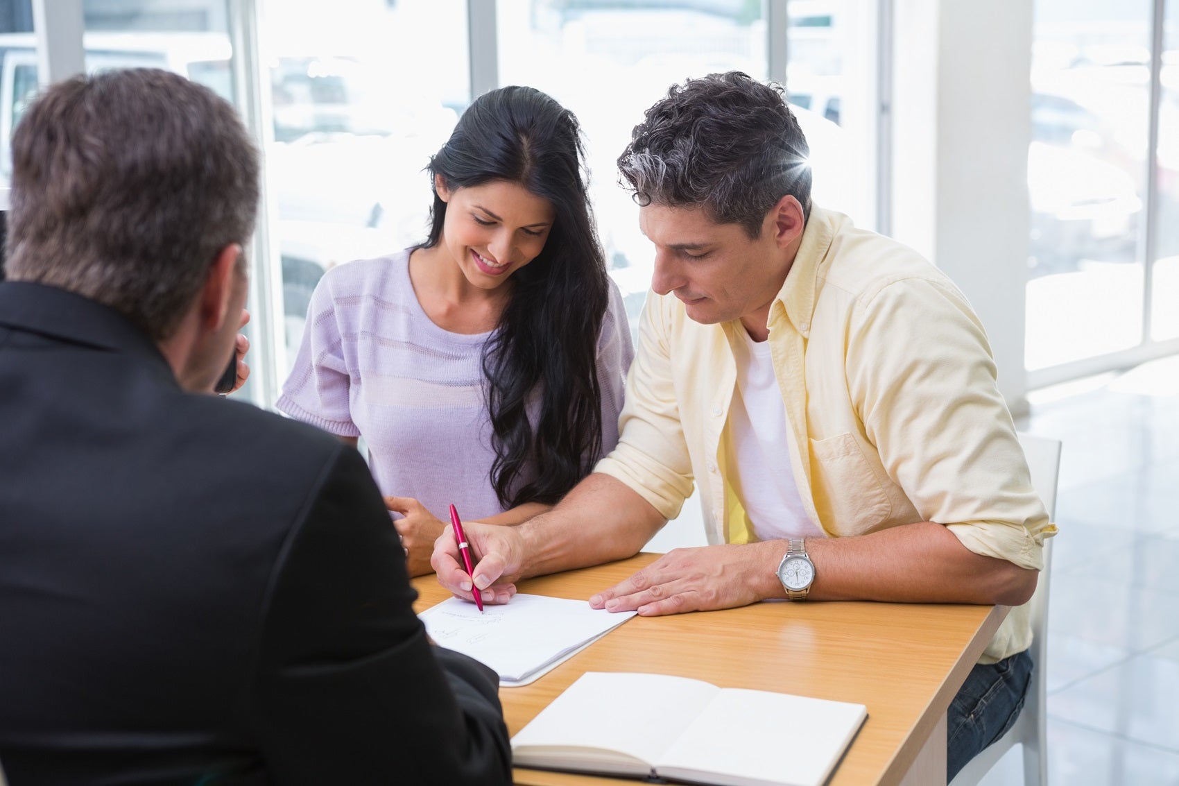 Couple signing paperwork for new VW vehicle from Volkswagen dealer near San Antonio TX 