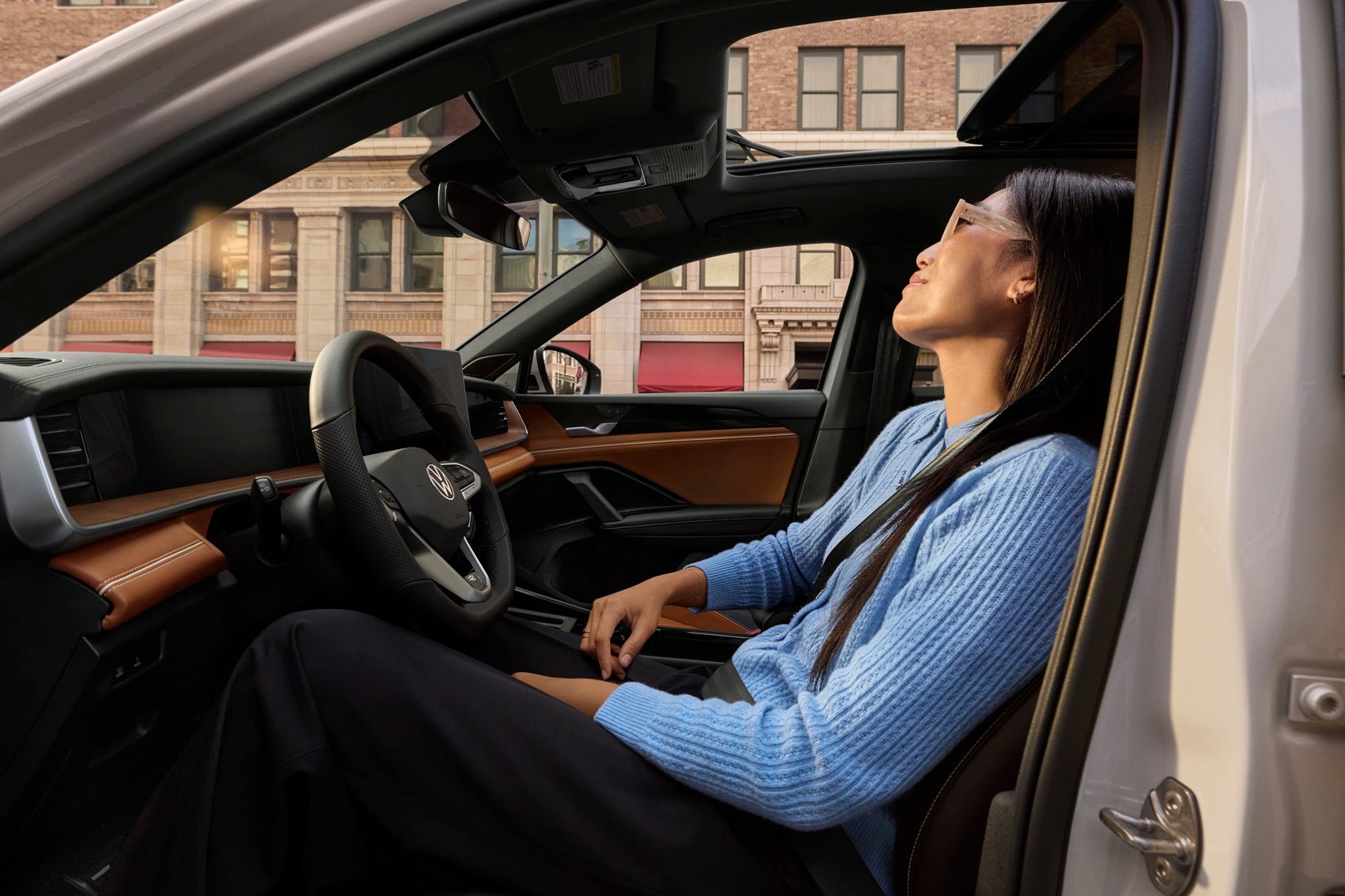 Woman sitting in the driver's seat of a Volkswagen Tiguan with the door open and relaxing looking out the window near San Antonio TX 